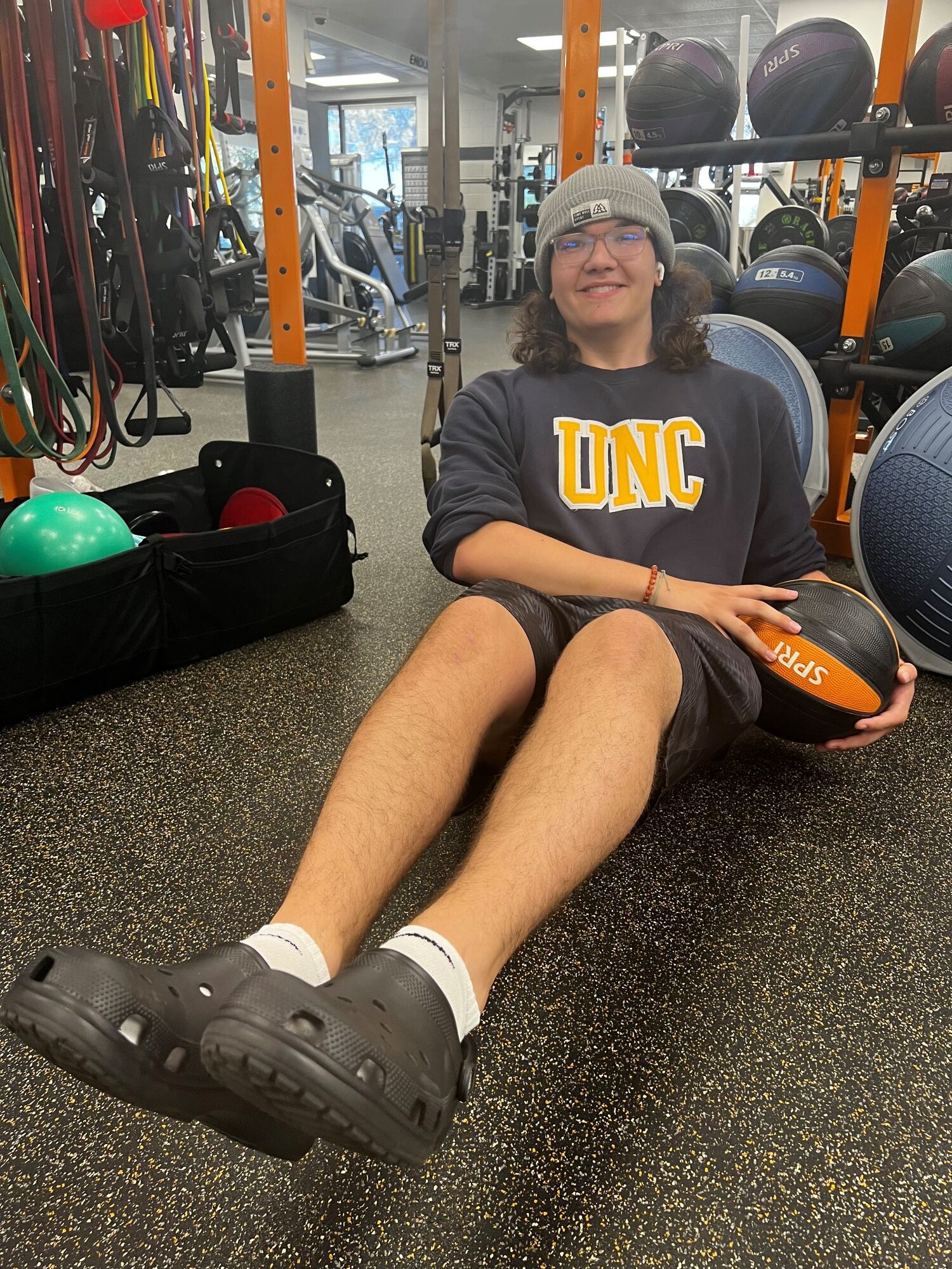Person sitting on the floor of AFAC gym exercising with a medicine ball
