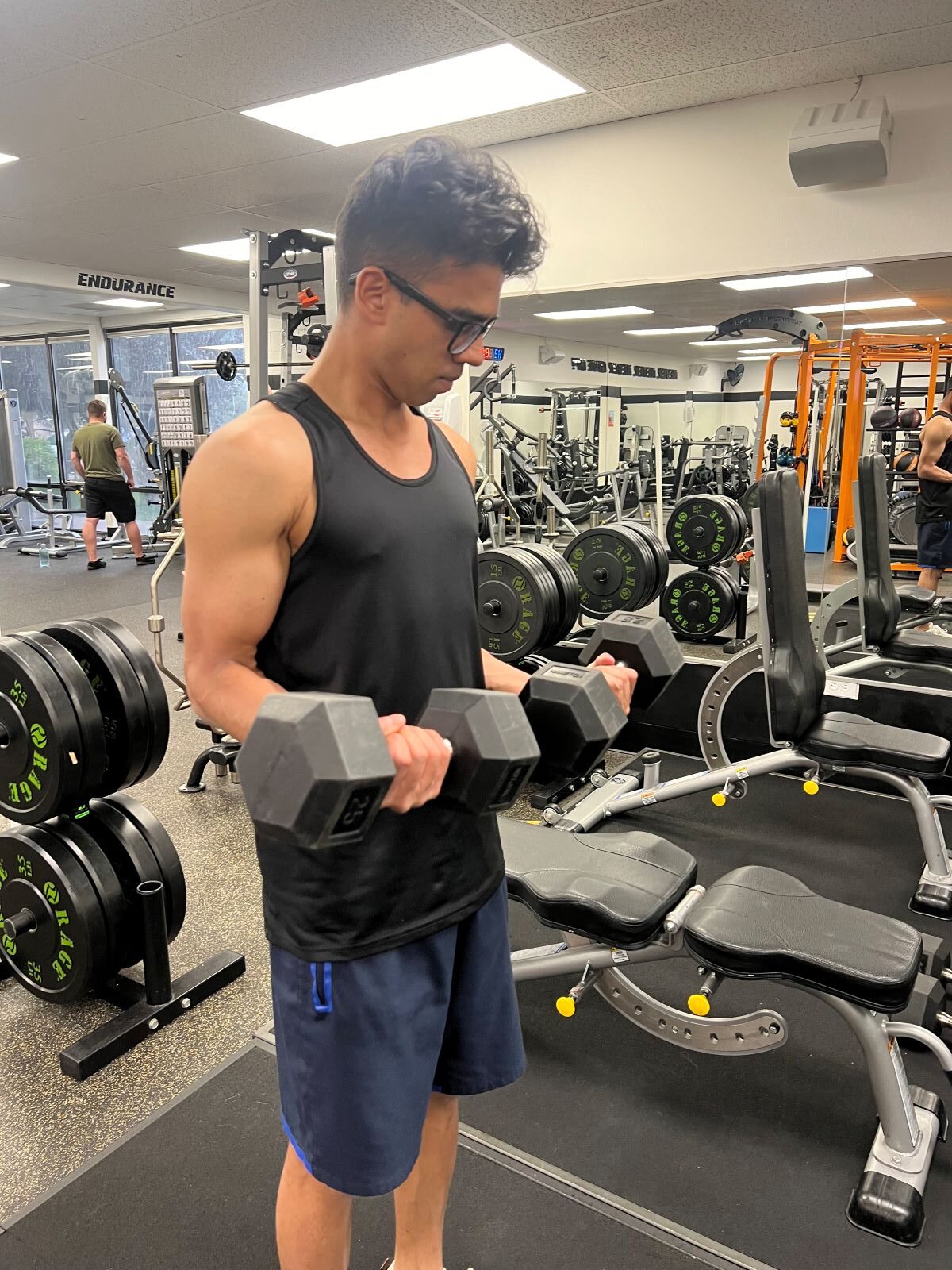 Man standing at AFAC gym with a pair of dumbbells in his hands