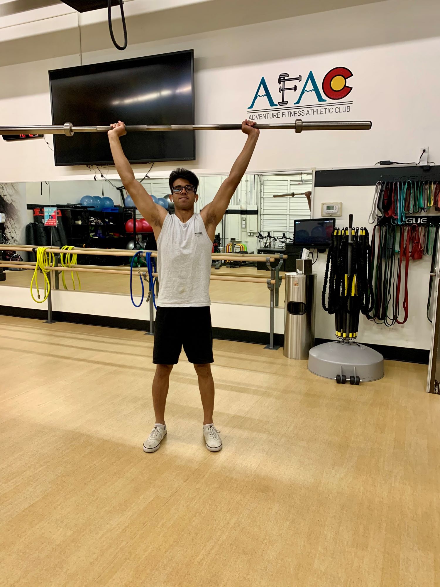 Man at AFAC gym performing an overhead press using a barbell