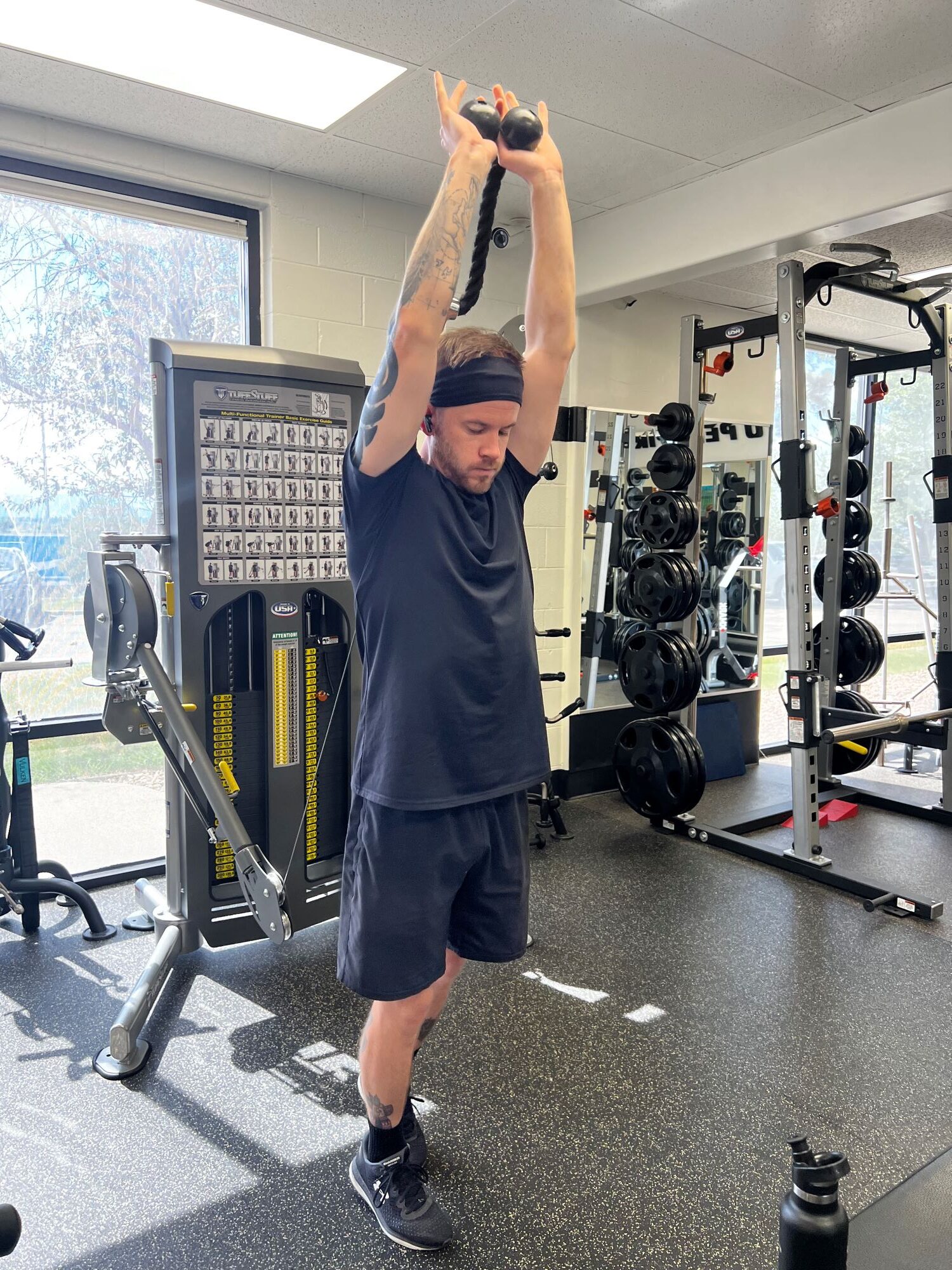 Man doing an overhead pull exercise on a cable machine at AFAC gym