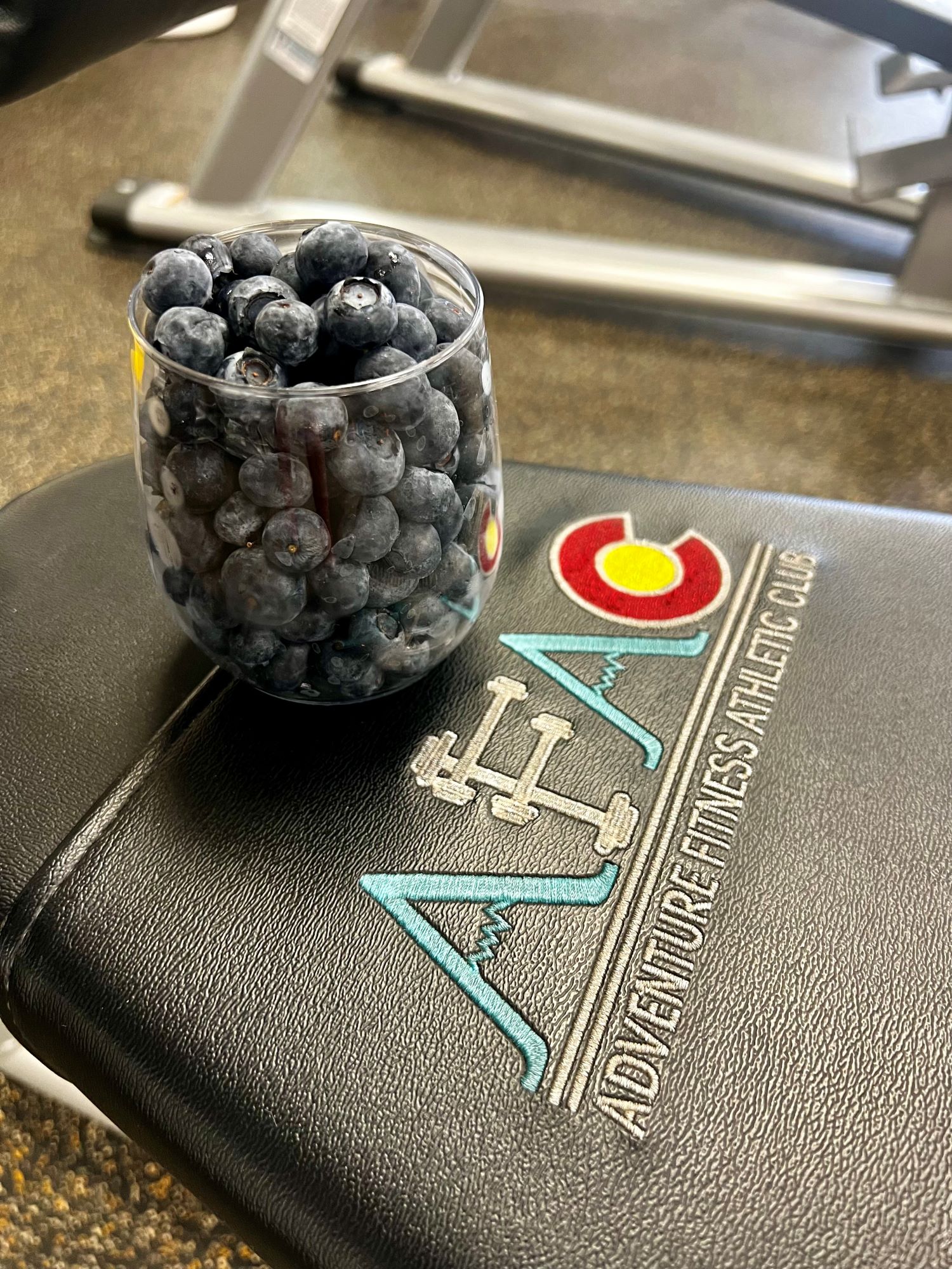 A glass full of blueberries sitting on a workout bench at AFAC gym