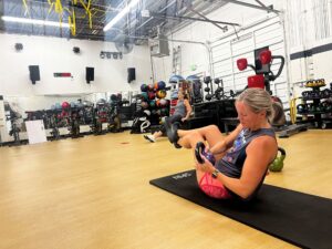 Woman performs Russian twists with a kettlebell at AFAC gym