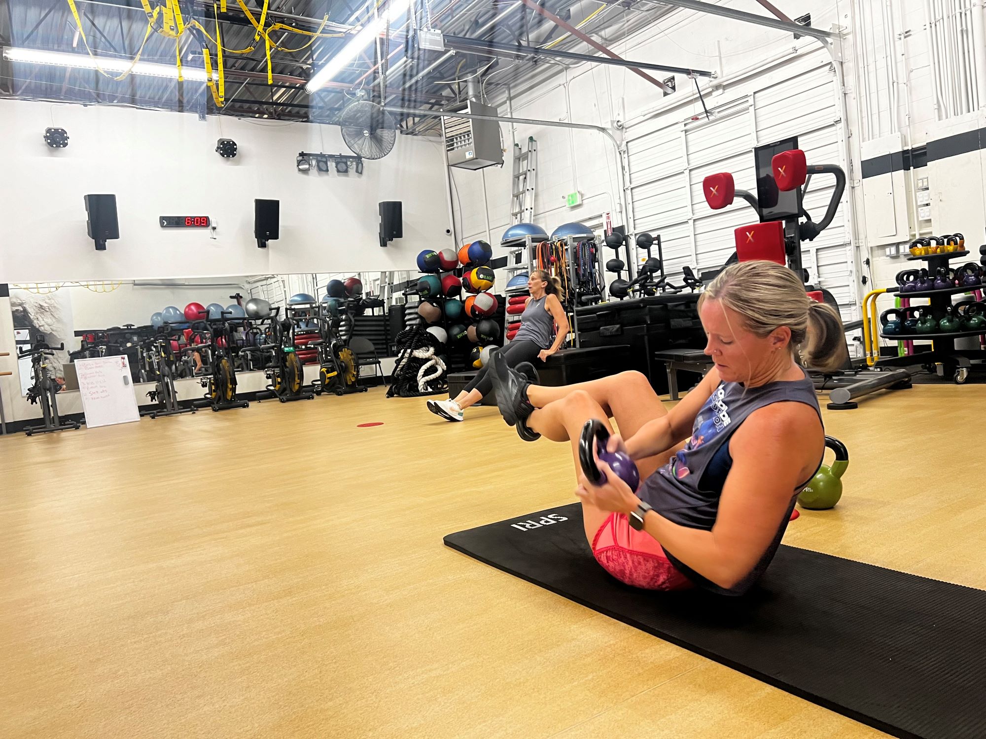 Woman performs Russian twists with a kettlebell at AFAC gym