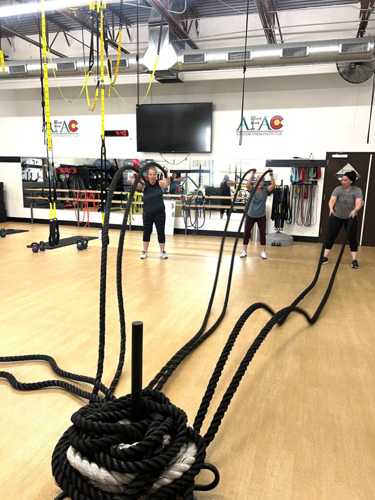 Three women work out with battle ropes at AFAC gym