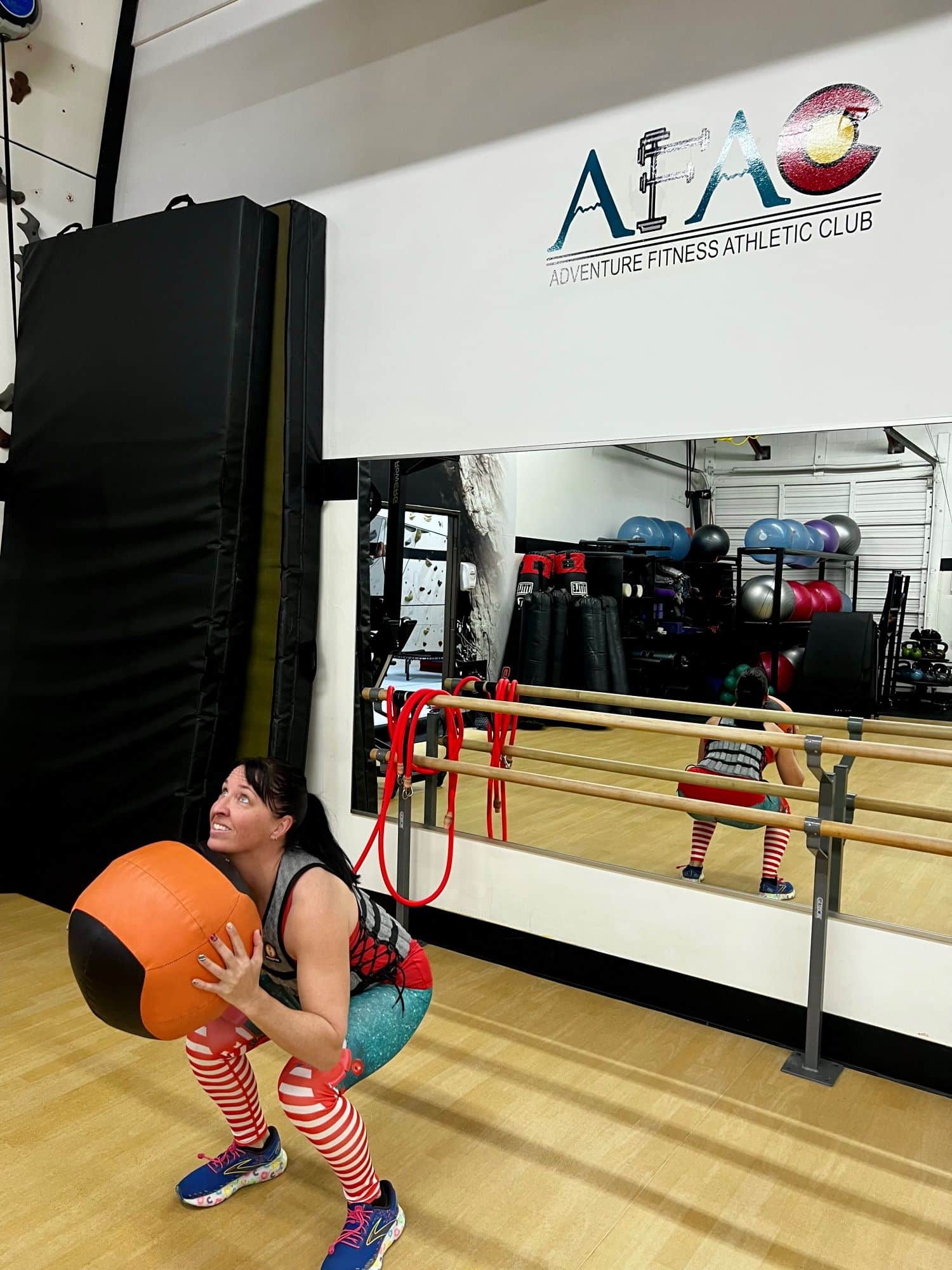 Woman squats while holding exercise ball in front of her at AFAC gym