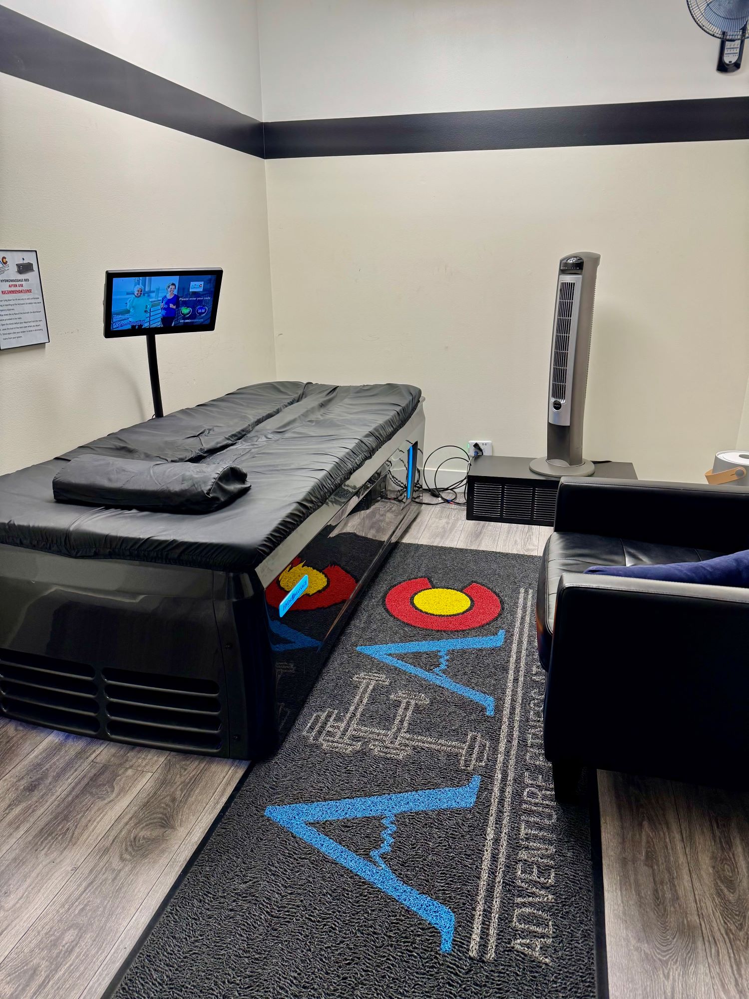 Photo of hydromassage bed at AFAC gym, showing operational screen, fan, and side chair in private hydromassage room