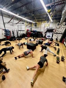 Group of people doing plank exercises on the floor of AFAC gym
