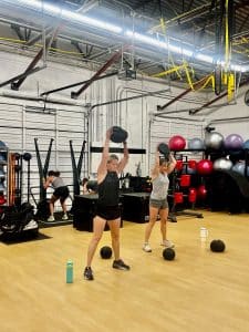 Two women hold medicine balls over their heads during a workout at AFAC gym