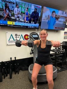 Young woman squats while holding two dumbbells in front of her at AFAC gym