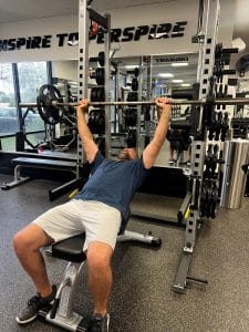 Man doing an incline bench press with a barbell at AFAC gym