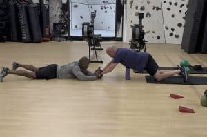 Personal trainer working with client on ab roller exercises at AFAC gym