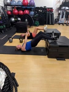 Two women doing floor exercises with kettlebells at AFAC gym