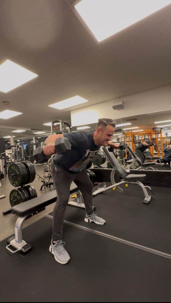 Man does a dumbbell reverse fly exercise at AFAC gym