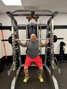 Man performs a back squat using a Smith machine at AFAC gym