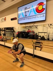 Man doing a squat while wearing a weighted vest at AFAC gym