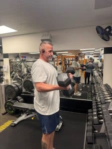 Man does biceps curls with dumbbells at AFAC gym