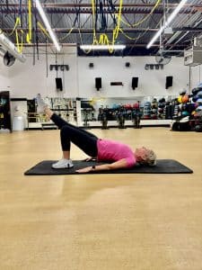 A woman performs a single-leg glute bridge exercise at AFAC gym