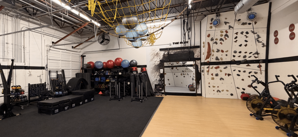 Inside of AFAC gym showing climbing wall, exercise equipment, turf