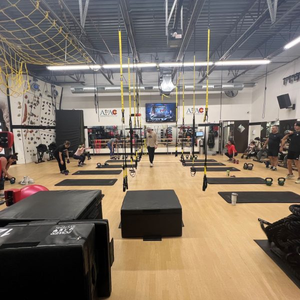 Instructor and several gym members work out during a fitness class at AFAC gym with amazing amenities